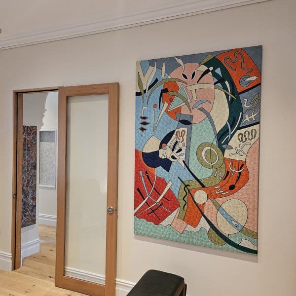 Colourful abstract canvas hung on clear perlon wires from an ArtiTeq Click Rail picture rail in a hallway