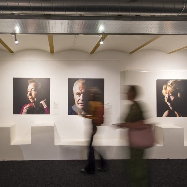 Gallery portraits hung on ArtiTeq Click Rail Pro picture rail with clear perlon wires in a modern exhibition space
