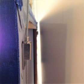 Artiteq Frame Hanger installed on stretcher (side view) | Hang Logic Artiteq Frame Hanger installed on the side of an artwork's stretcher with a hanging wire threaded through - Hang Logic.