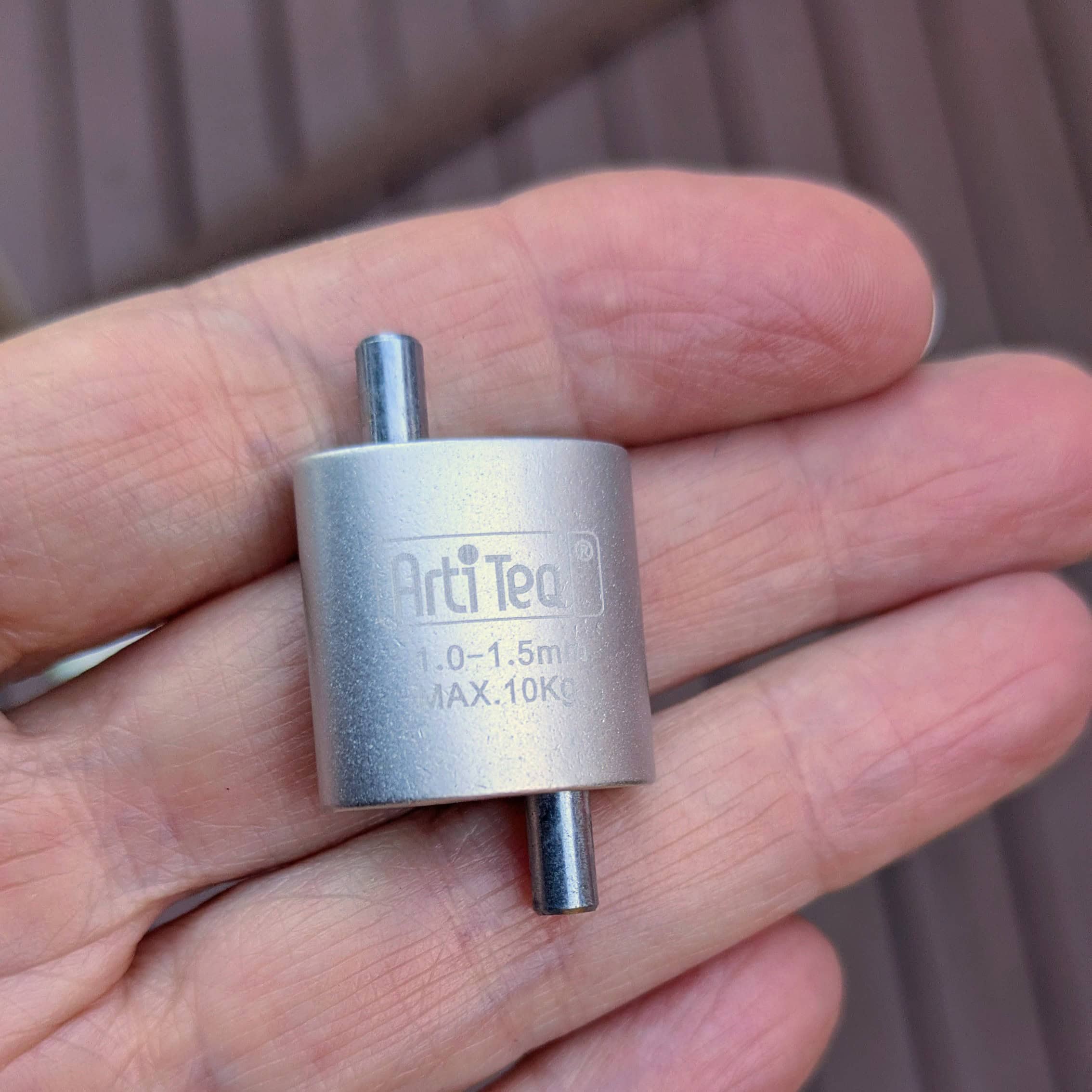 Small silver ArtiTeQ Loop Hanger resting across the fingers of a hand to show its size.