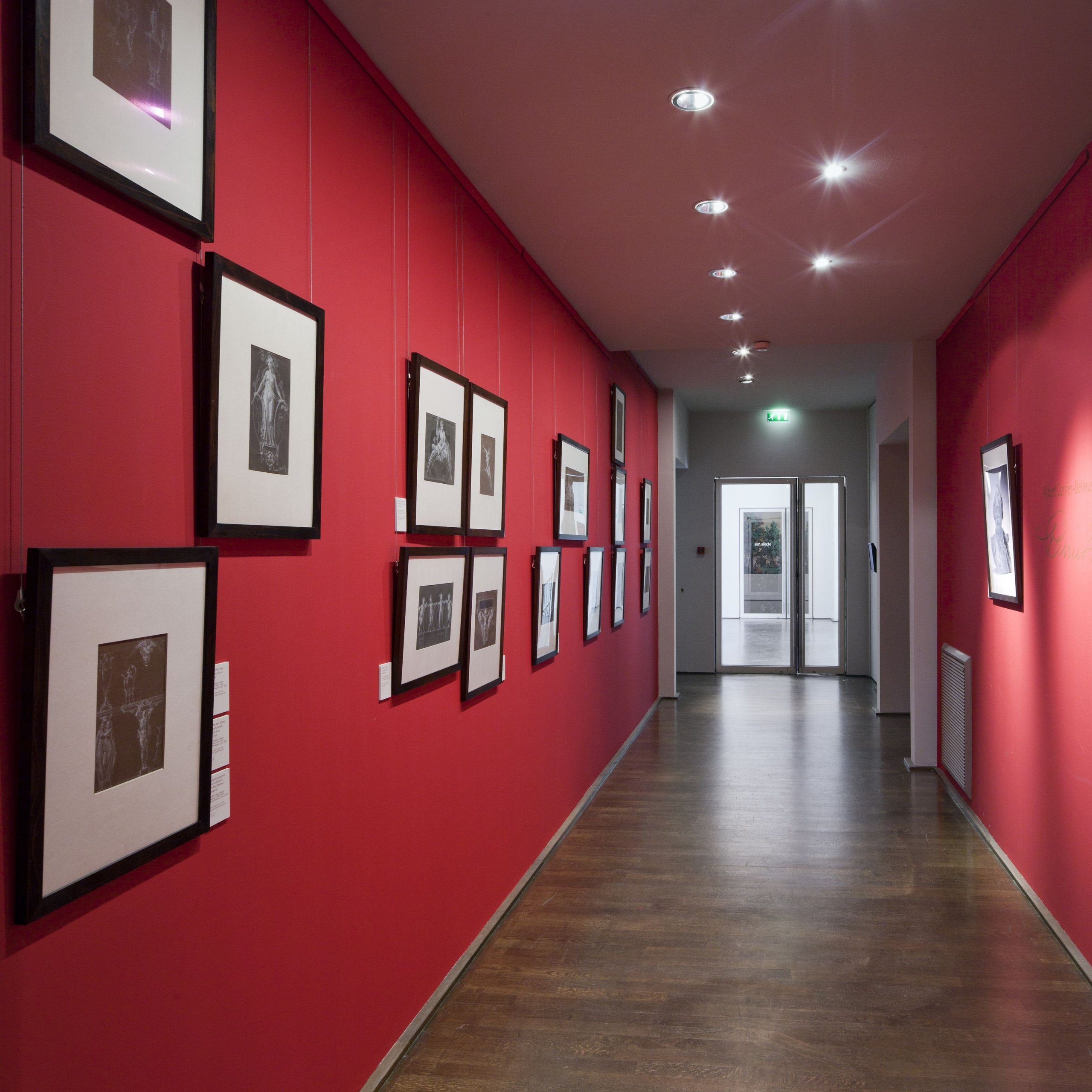 ArtiTeq Primer Click Rail Painted Redย Framed photos on red gallery wall hung from paintable ArtiTeq primer Click Rail picture rail with clear perlon wires