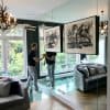Man adjusts abstract prints hung on clear perlon wires from an ArtiTeq Click Rail picture rail fixed to a mirrored wall