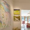 Three paintings hung on clear Twister 2 mm perlon cables attached to a white ArtiTeq picture rail in a light‑filled hallway, supplied by Hang Logic.