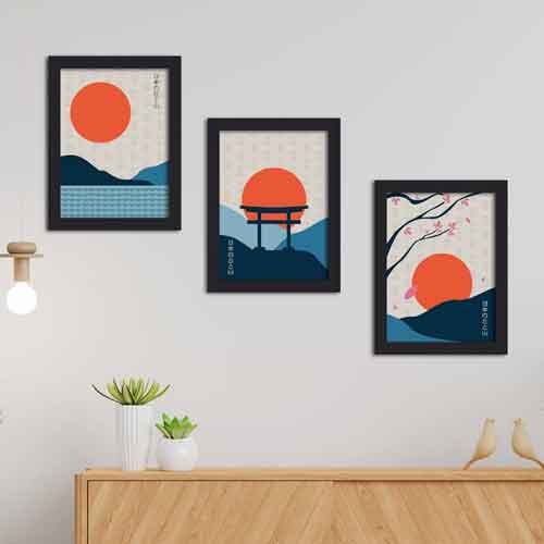 Three framed artworks with orange sun motifs hanging on a wall using picture rails