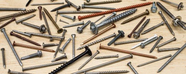 Assortment of nails and screws spread out, illustrating traditional hanging methods.