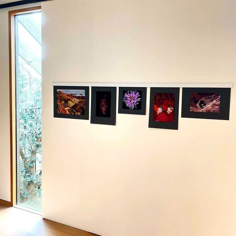 Photo of an ArtiTeq Info Rail mounted on a white wall displaying five photos, elegantly arranged in a minimalistic and modern setting.