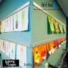 Photo of ArtiTeq Info Rail showcasing children's artwork and crafts in a classroom setting, mounted on a teal wall. Available at Hang Logic.