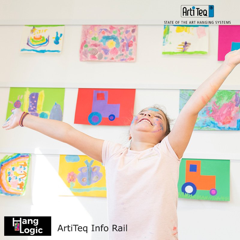 Smiling young student in front of colorful classroom artwork displayed on Info Rail art rails.