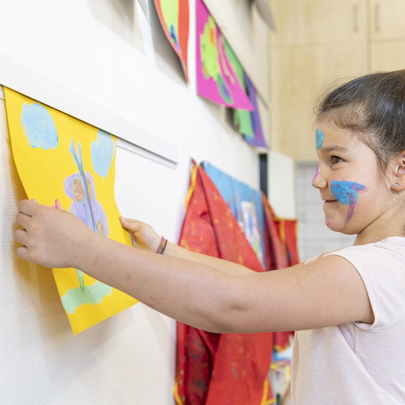 artiteq-inforail-classroom-art-display Young girl sliding her artwork into an Artiteq InfoRail in a classroom setting.