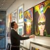 Gallery owner adjusting colourful canvases hung from Combi Rail PRO Light with integrated LED spots