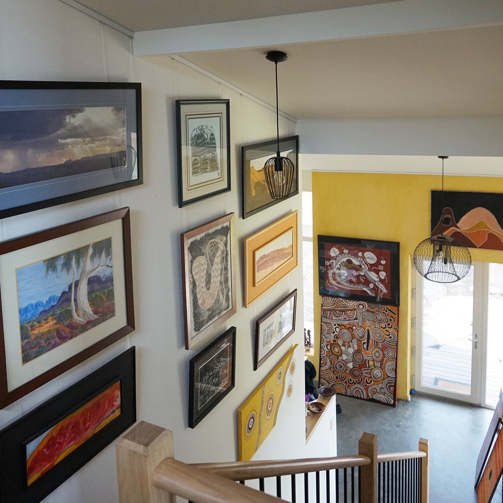 Staircase wall covered with framed art hung on clear Twister Cliq2Fix perlon wires attached to a white ArtiTeq picture rail, supplied by Hang Logic.