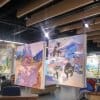Large square canvases suspended from ArtiTeq Top Rail fixed to timber ceiling baffles in an art studio exhibition space