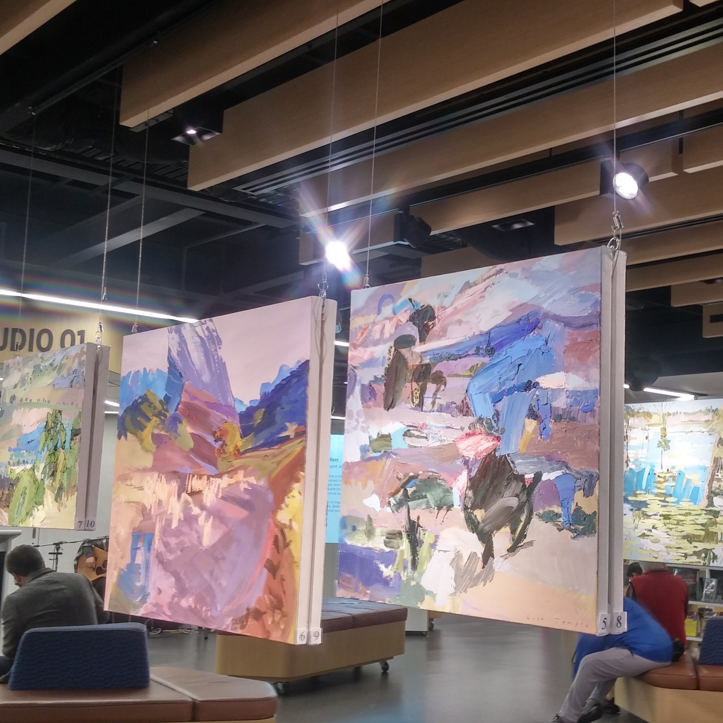 Large square canvases suspended from ArtiTeq Top Rail fixed to timber ceiling baffles in an art studio exhibition space