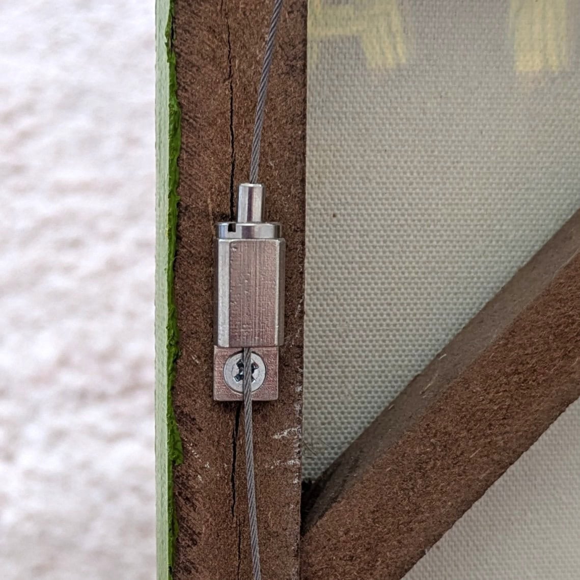 Artiteq Frame Hanger mounted high on frame | Hang Logic Artiteq Frame Hanger screwed high on frame side with steel hanging wire threaded through - Hang Logic.