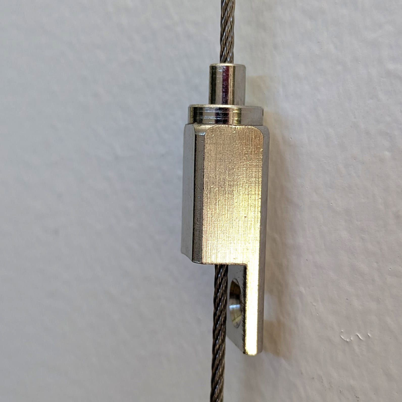 Artiteq Frame Hanger on steel wire close-up | Hang Logic Close-up of Artiteq Frame Hanger on steel hanging wire, showing the compact metal body - Hang Logic.