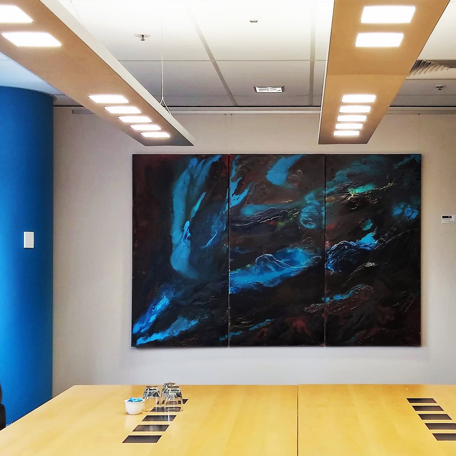 Professional corporate boardroom featuring a massive abstract blue triptych artwork installed neatly using a wall-mounted ArtiTeq rail system.