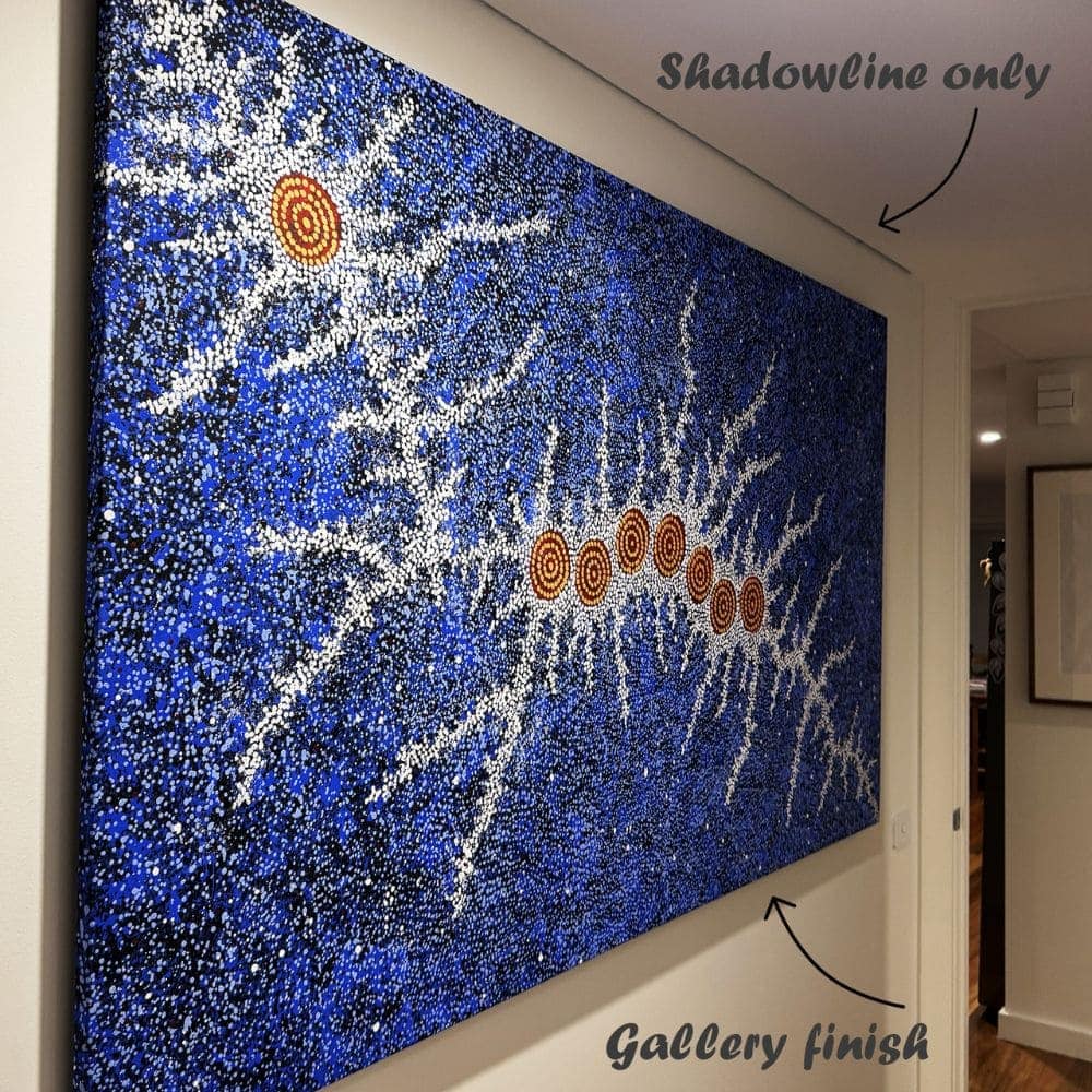 ArtiTeq Shadowline Drywall Picture Rail Large blue dot aboriginal painting hanging on thin wires beneath a concealed ArtiTeq Shadowline Drywall picture rail, with only a slim ceiling shadow line gap visible.