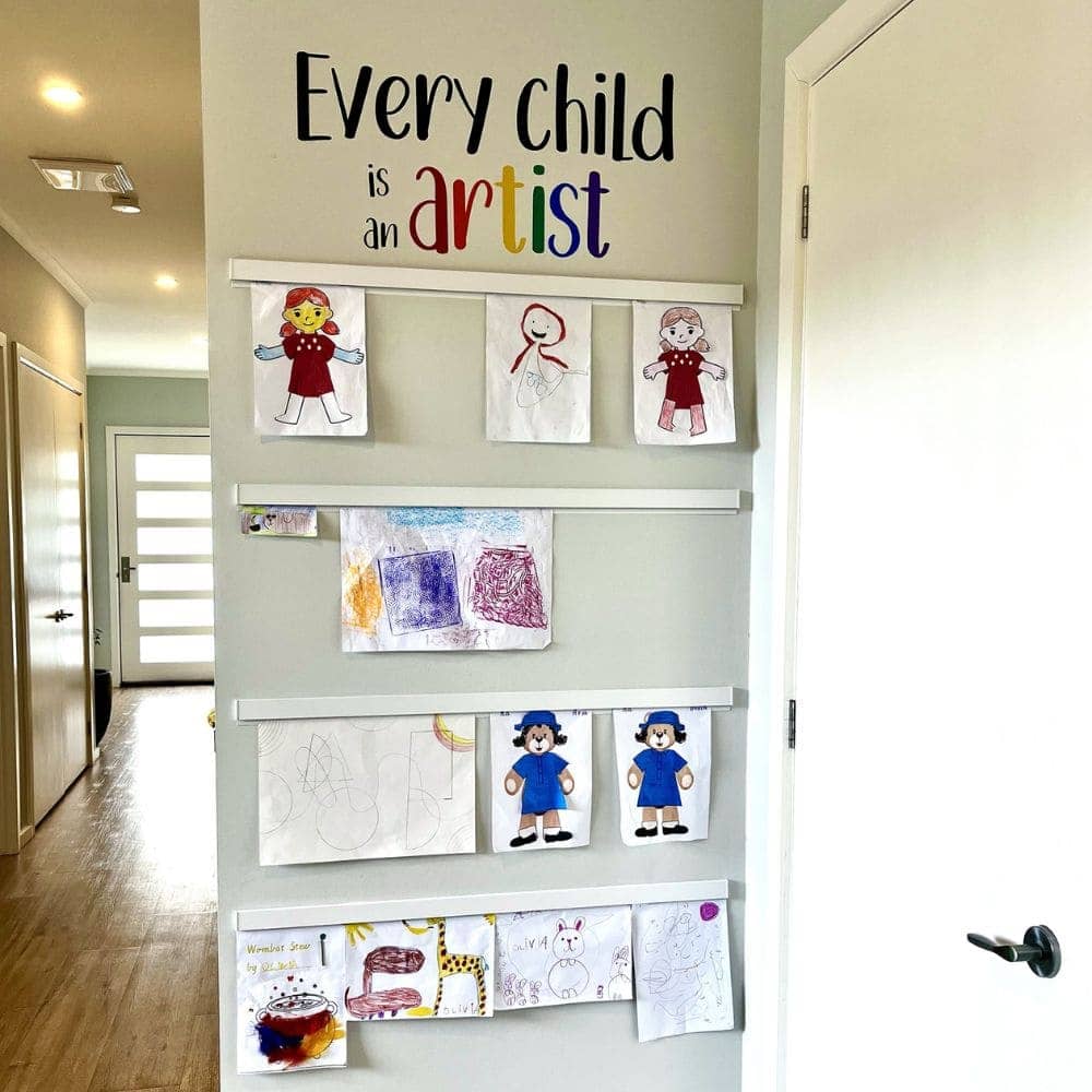 Children’s drawings displayed on white Info Rail strips in a hallway, beneath the words “Every child is an artist”.