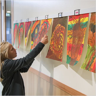 The Info Rail lets teachers and students slide in drawings, paintings or posters, then swap them out as soon as new work is made